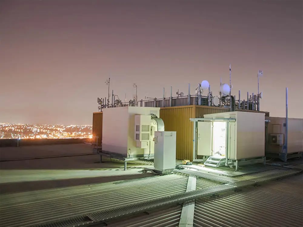 Rooftop of a building with RF antannae with skyline in background at night